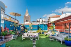 an outdoor patio with lawn furniture and umbrellas on the roof top terrace, next to a clock tower in the background