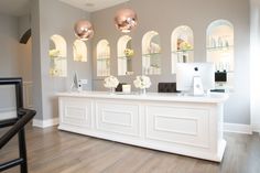 the front desk of a nail salon with gold and white decorations on it's walls