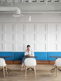 a man is sitting on a bench in the middle of a room with blue and white walls