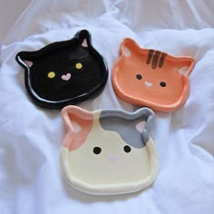 three cat shaped dishes on a white sheet