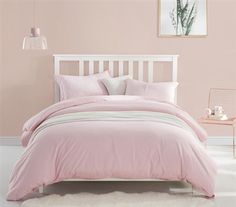 a bed with pink sheets and pillows in a room