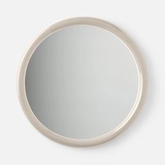 a white round mirror hanging on the wall