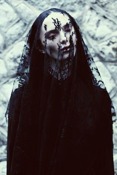 a woman with white makeup and black veil