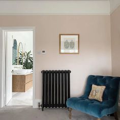 a blue chair sitting in front of a window next to a radiator