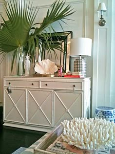 a living room filled with furniture and a large palm leaf on top of a dresser