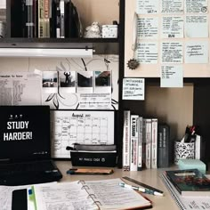 a laptop computer sitting on top of a wooden desk next to books and binders