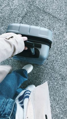 a person holding onto a piece of luggage on the ground