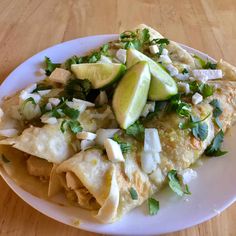 a white plate topped with nachos covered in cheese and avocado slices