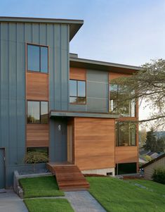 a modern house with wood and metal sidings on the outside, grass in front