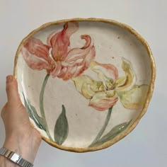 a hand holding a bowl with flowers painted on it