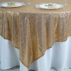 two white plates with gold sequins on them are sitting on a round table