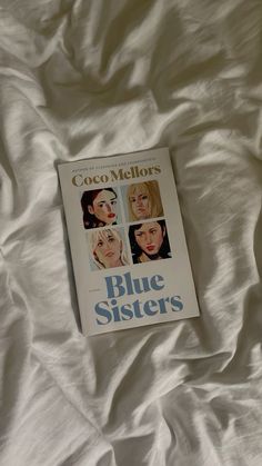 the book blue sisters is laying on top of white sheets