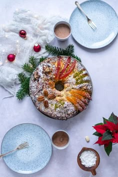 a table topped with plates and bowls filled with desserts next to christmas decorations on top of a white table cloth