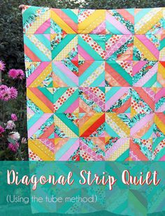 a colorful patchwork quilt hanging in front of some flowers