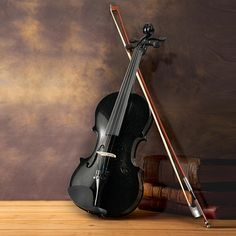 a black violin and two sticks on a wooden table in front of a brown wall