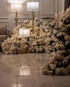 a living room filled with lots of flowers next to a table topped with white candles