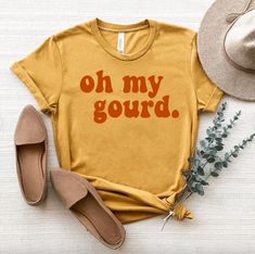 Embrace the whimsical spirit of autumn with our 'Oh My Gourd' Mustard Fall Shirt. Crafted from soft and breathable fabric, this shirt blends comfort with seasonal charm. Whether you're enjoying pumpkin spice everything, exploring pumpkin patches, or cozying up by the fire, our shirt captures the essence of fall in a playful and stylish design. Key Features: Soft and Breathable Fabric: Made from premium materials for all-day comfort. Charming Design: Features 'Oh My Gourd' in a fun and whimsical Oh My Gourd, Whimsical Fonts, Pumpkin Spice Everything, Pumpkin Patches, Fall Shirt, Autumn Theme, Fall Shirts, Fall Wardrobe, Gourds