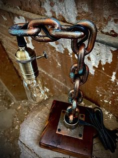 a lamp that is sitting on top of a wooden table with chains hanging from it