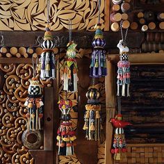 several colorful necklaces hanging from hooks on a wooden wall with carved wood paneling