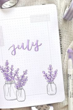 a notebook with purple flowers and the word july written on it next to some markers