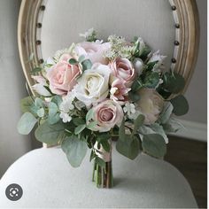 a bridal bouquet sitting on top of a chair with greenery and flowers in it