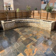 an outdoor patio with stone walls and brick seating area, surrounded by wooden fence posts