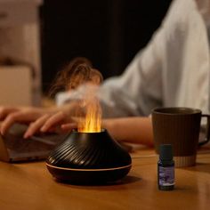 a person sitting at a table using a laptop with a flame coming out of it