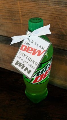 a green bottle with a tag on it sitting on top of a wooden table next to a sign