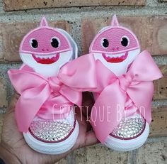 someone is holding up their pink shoes with a shark face on the front and bottom