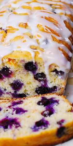 a loaf of blueberry bread with white glaze on top is sitting on a plate