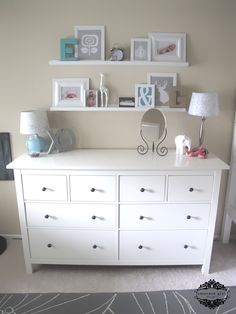 a white dresser sitting in a bedroom next to a window with pictures on the wall