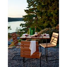 an outdoor table with two chairs next to it and a bottle of wine on the table