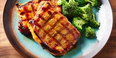 a plate with meat and broccoli on it sitting on top of a wooden table