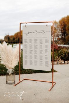 a wedding seating chart is displayed in a vase with some pamodia on it