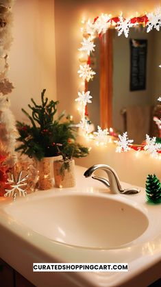 a bathroom sink with christmas decorations and lights on the wall behind it, in front of a mirror