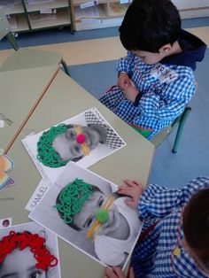 two children are sitting at a table making pictures