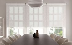 a dining room table with white chairs and a vase on the table in front of it