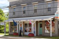 an old fashioned store front on the corner of a street with flags hanging from it's windows