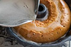 a bundt cake with icing being poured into it and on top of the pan