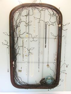 a wall mounted jewelry rack with branches and beads hanging from it's sides on a white wall