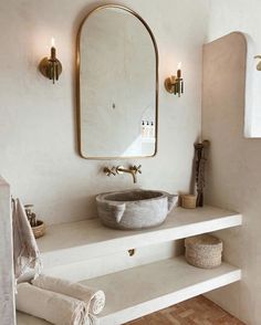 a bathroom with a sink, mirror and towels on the shelf in front of it