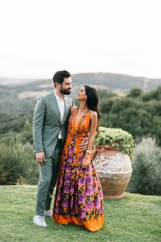 a man and woman standing next to each other on top of a lush green field