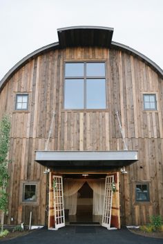 a large wooden building with an open front door and white drapes on the windows