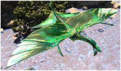 a green bird flying through the air with trees in the background