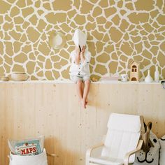 a person sitting on top of a chair in front of a wall with giraffe print