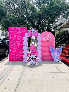 a pink hello kitty sign on the sidewalk