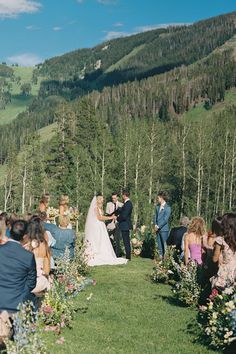 a bride and groom standing at the end of their wedding ceremony with mountains in the background