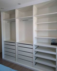 an empty closet with white shelves and drawers