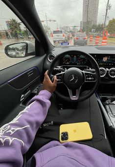 a person driving a car in the rain with their hands on the steering wheel and dashboard