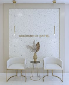 two white chairs sitting next to each other in front of a wall with writing on it